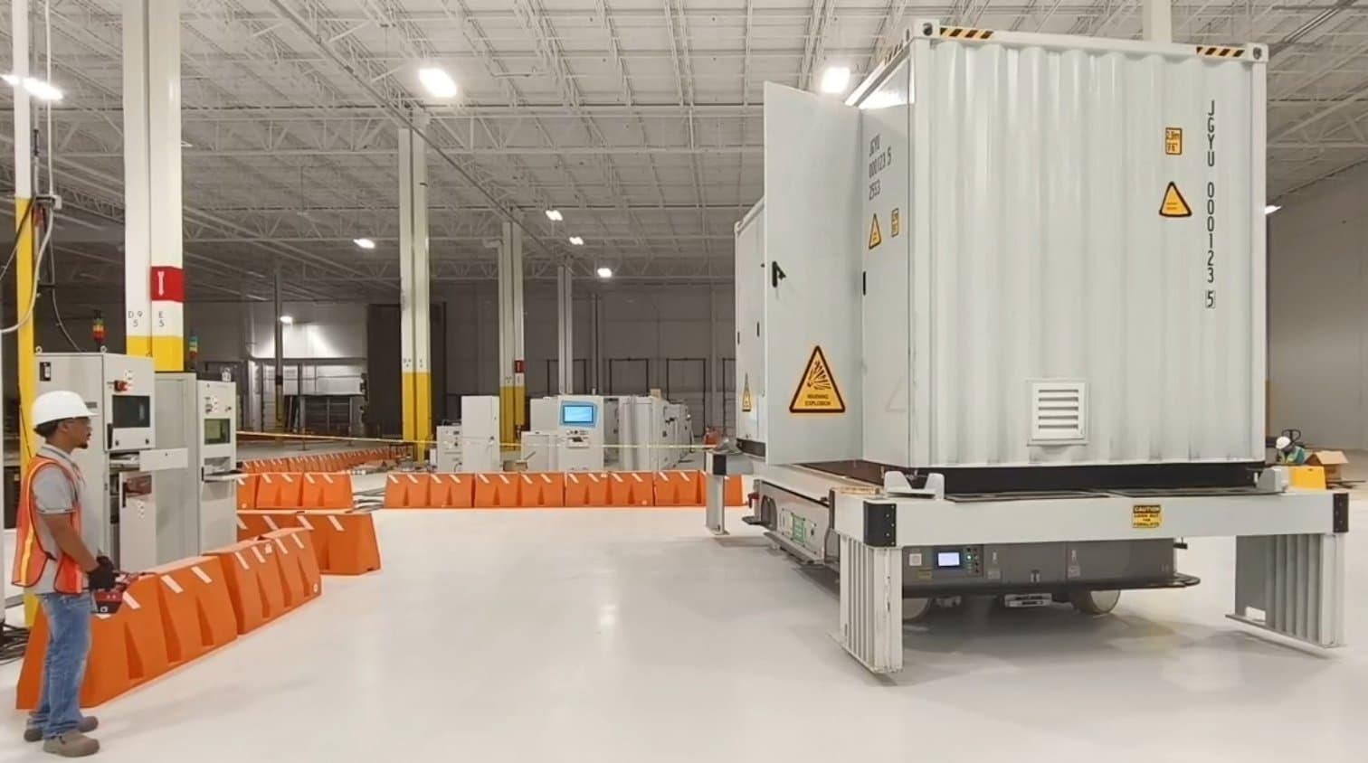 Üretim tesisinde enerji depolama (BESS) konteynerini taşıyan ağır yük AGV — üretici uygulama görseli