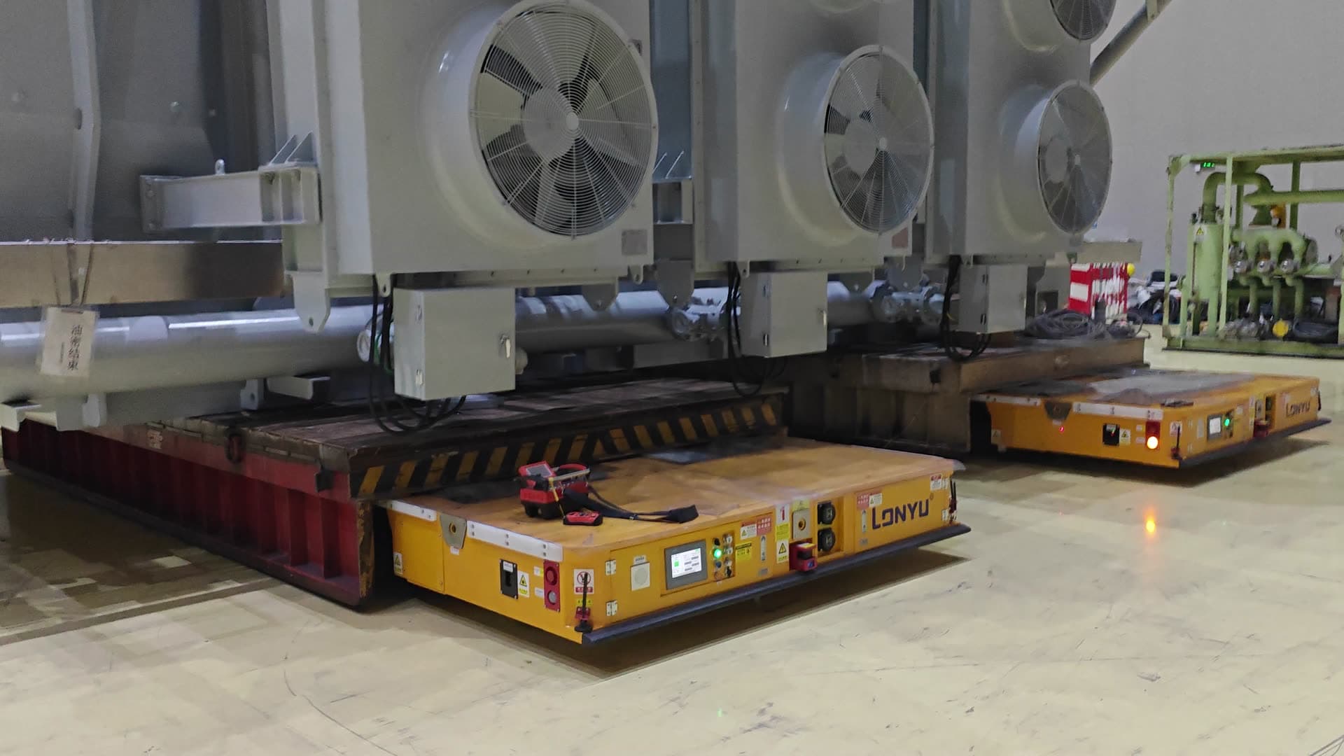 İki Lonyu Robot ağır yük AGV'si bir transformatörü birlikte taşıyor